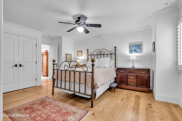 bedroom featuring light wood-type flooring, a closet, crown molding, and baseboards