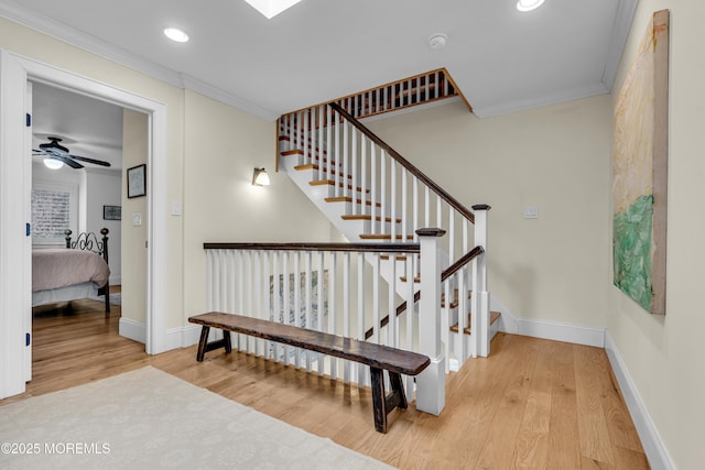 stairway featuring ceiling fan, recessed lighting, wood finished floors, baseboards, and crown molding