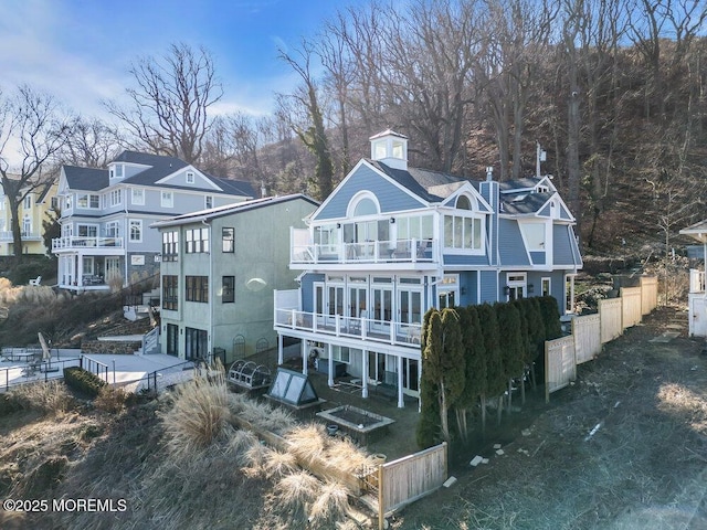 rear view of property featuring driveway, a garage, a balcony, a residential view, and fence