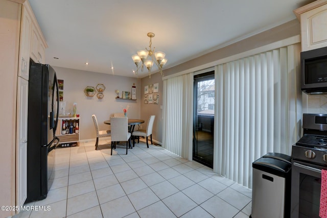 kitchen with gas range, light tile patterned flooring, a chandelier, and black fridge