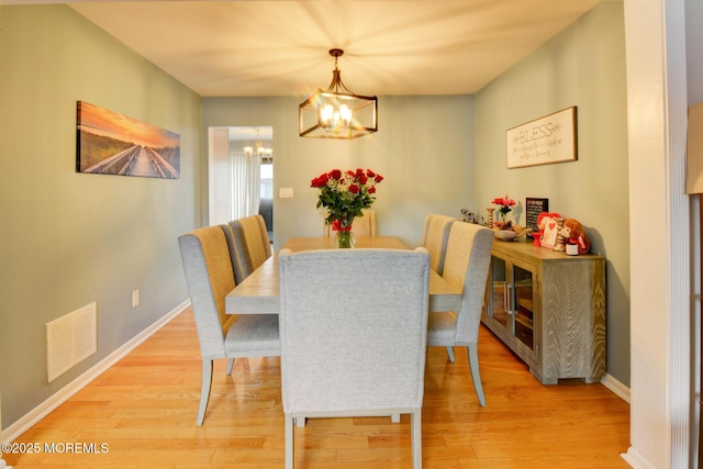 dining space with a notable chandelier and light hardwood / wood-style flooring