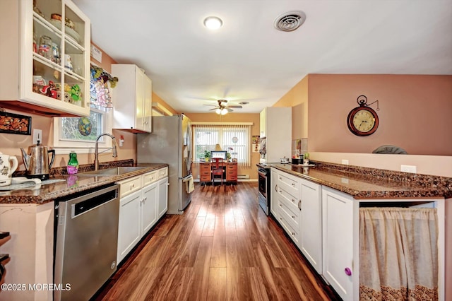 kitchen with appliances with stainless steel finishes, sink, dark stone countertops, and white cabinets