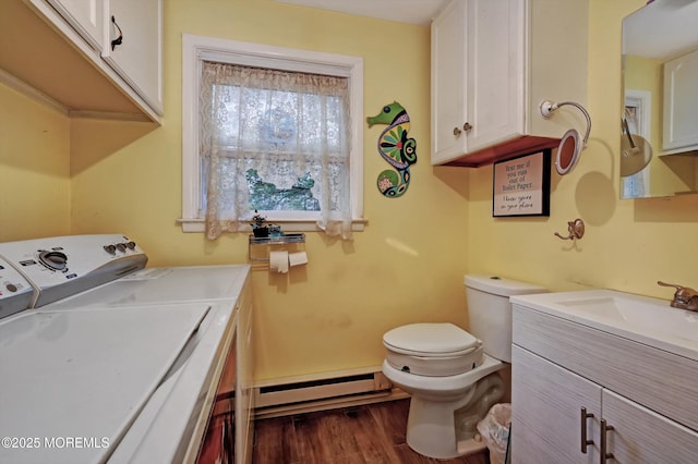 laundry area with washing machine and dryer, a baseboard heating unit, sink, and dark hardwood / wood-style flooring