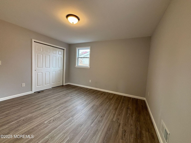 unfurnished bedroom with dark wood-type flooring and a closet