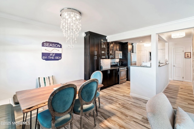 dining space featuring an inviting chandelier, light hardwood / wood-style flooring, and ornamental molding