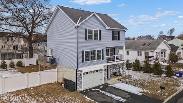 view of front of property with cooling unit, a balcony, and a garage