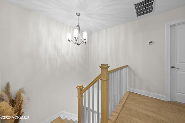 staircase with hardwood / wood-style flooring and a chandelier