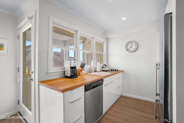 kitchen with ornamental molding, appliances with stainless steel finishes, a sink, and white cabinetry