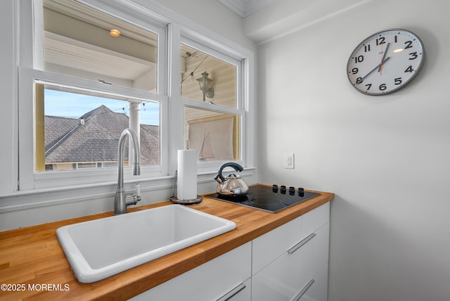 interior space with wood finished floors, a sink, white cabinetry, and black electric cooktop