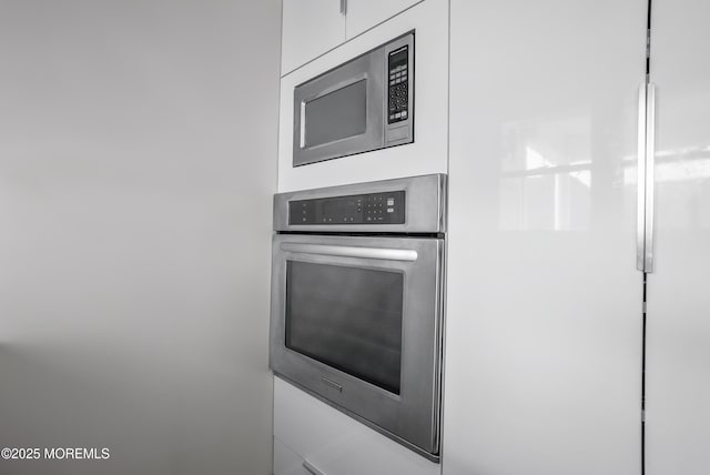 interior details with stainless steel appliances, white cabinetry, and mail area