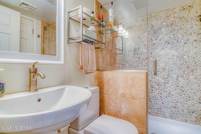 bathroom featuring a stall shower, visible vents, a sink, and toilet