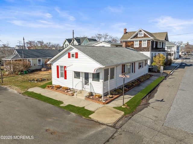 view of front of house with a chimney, a residential view, and a shingled roof