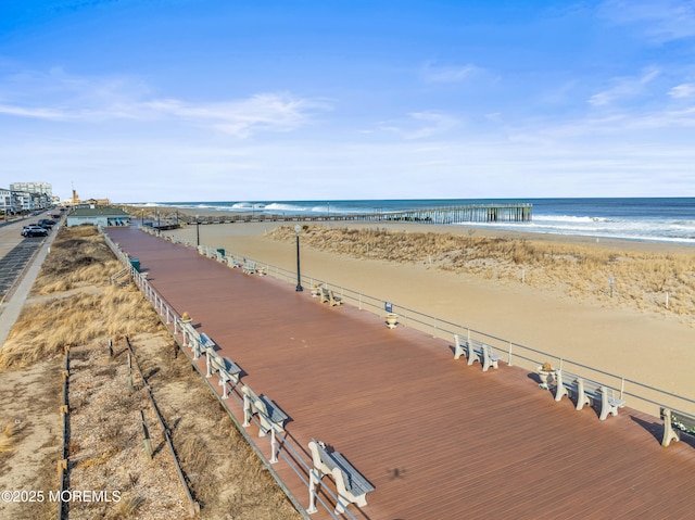 property view of water featuring a pier and a beach view