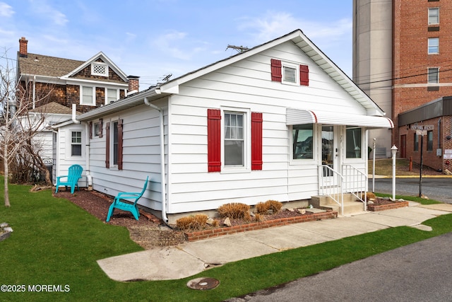 bungalow-style home featuring entry steps and a front lawn