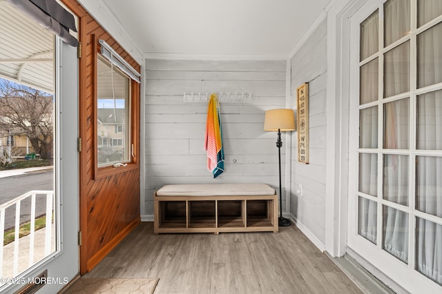 mudroom with light wood finished floors, wooden walls, and baseboards