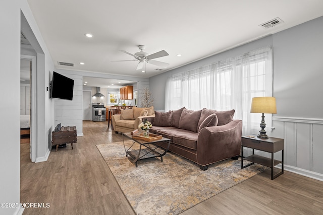 living room with visible vents, ceiling fan, and wood finished floors