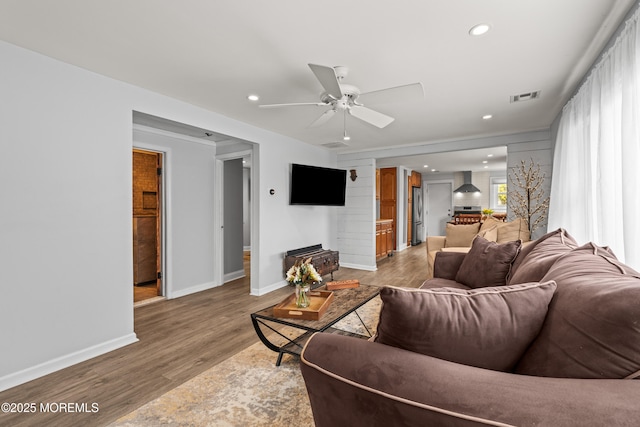 living room with a ceiling fan, visible vents, light wood finished floors, baseboards, and recessed lighting