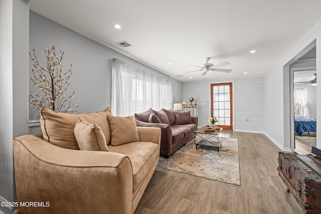 living room featuring plenty of natural light, ceiling fan, visible vents, and wood finished floors