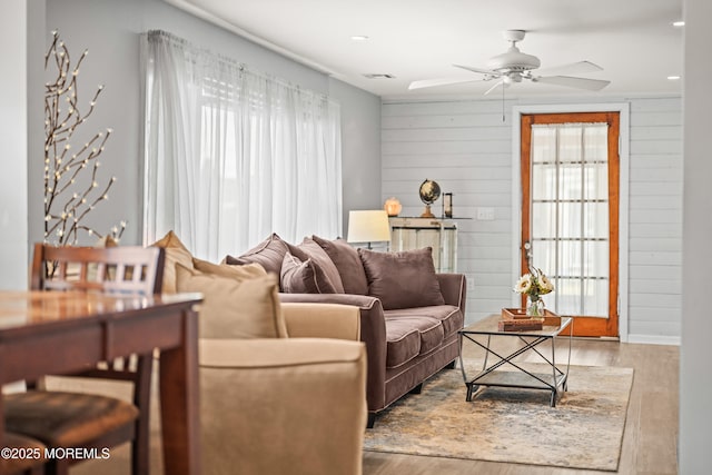 living area featuring visible vents, wood finished floors, a ceiling fan, and wood walls