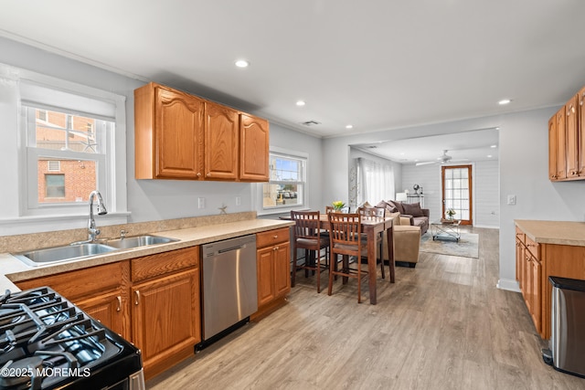 kitchen featuring open floor plan, dishwasher, range with gas stovetop, light wood-style flooring, and a sink