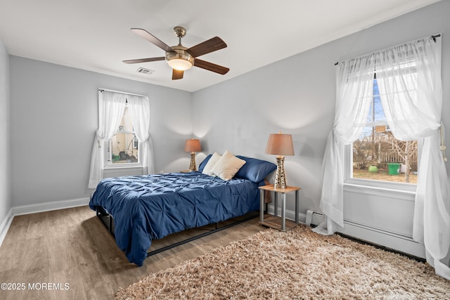 bedroom featuring ceiling fan, visible vents, baseboards, and wood finished floors