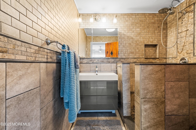 full bathroom featuring tiled shower and vanity