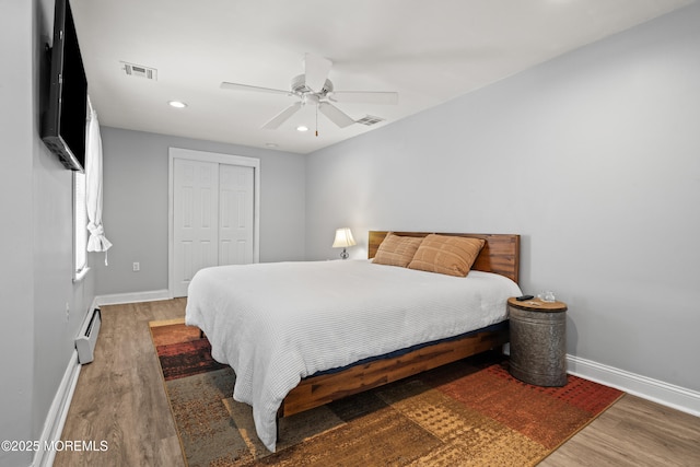 bedroom with a closet, visible vents, baseboards, and wood finished floors