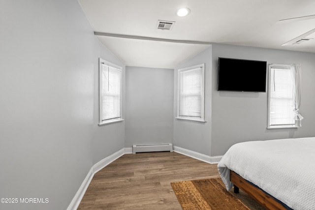 bedroom with visible vents, baseboards, lofted ceiling, baseboard heating, and wood finished floors