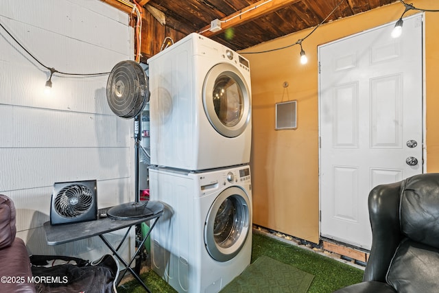 clothes washing area featuring stacked washer / drying machine, wooden ceiling, and laundry area