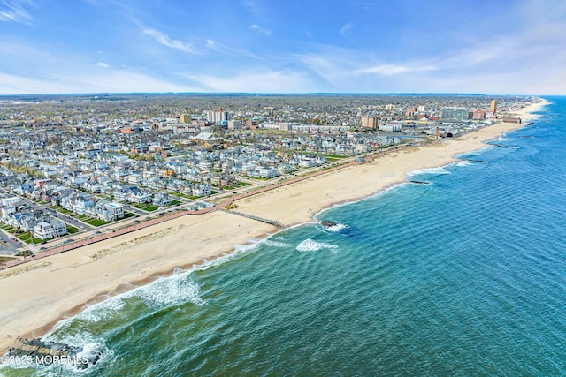 drone / aerial view with a water view, a view of city, and a beach view