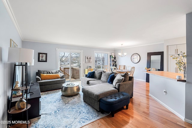 living room featuring crown molding, a chandelier, and light wood-type flooring