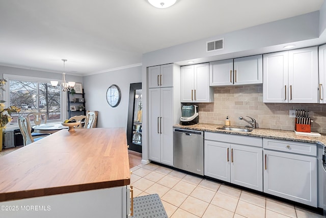 kitchen featuring pendant lighting, wood counters, sink, backsplash, and stainless steel dishwasher