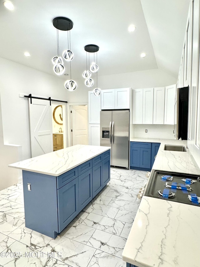 kitchen featuring blue cabinetry, white cabinetry, decorative light fixtures, stainless steel fridge, and a barn door