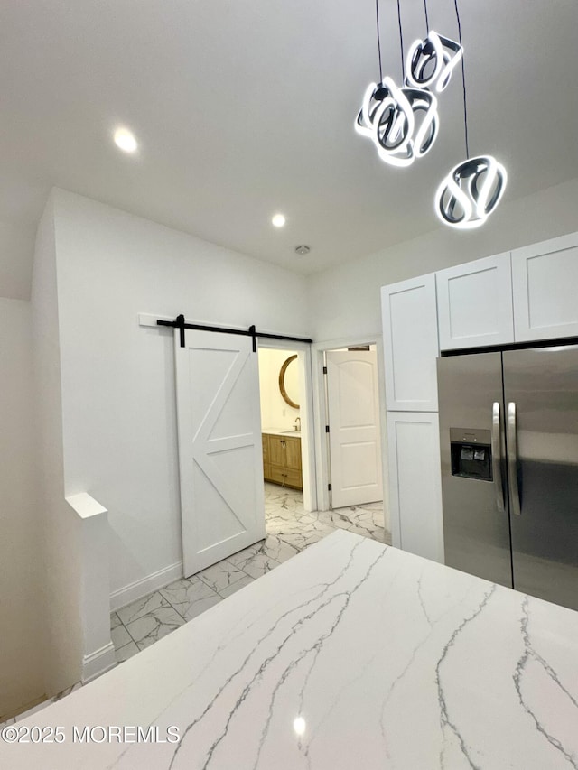 bedroom with connected bathroom, stainless steel fridge with ice dispenser, a closet, and a barn door