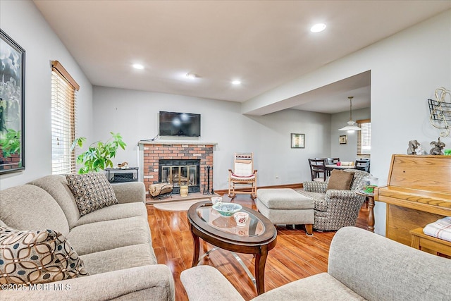 living room with a brick fireplace and hardwood / wood-style floors