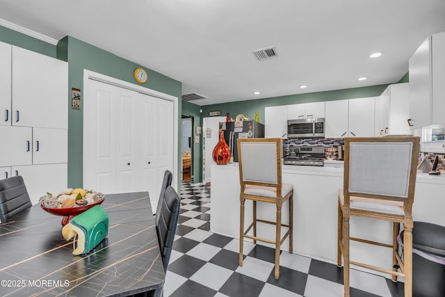 kitchen with tasteful backsplash, appliances with stainless steel finishes, a breakfast bar, and white cabinets