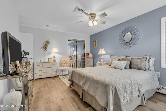 bedroom featuring ornamental molding, light hardwood / wood-style floors, a closet, and ceiling fan