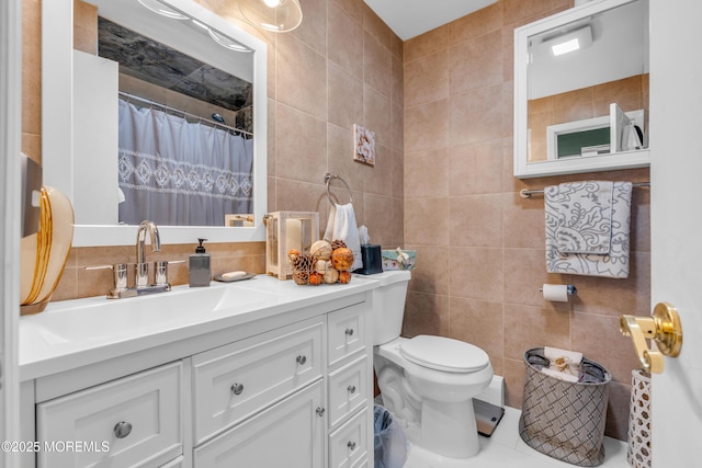 bathroom featuring walk in shower, vanity, toilet, and tile walls