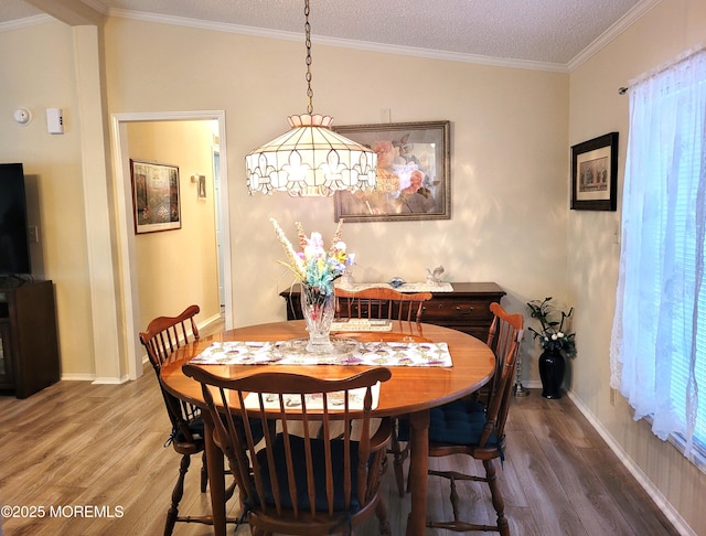 dining room with hardwood / wood-style floors, crown molding, vaulted ceiling, and a textured ceiling