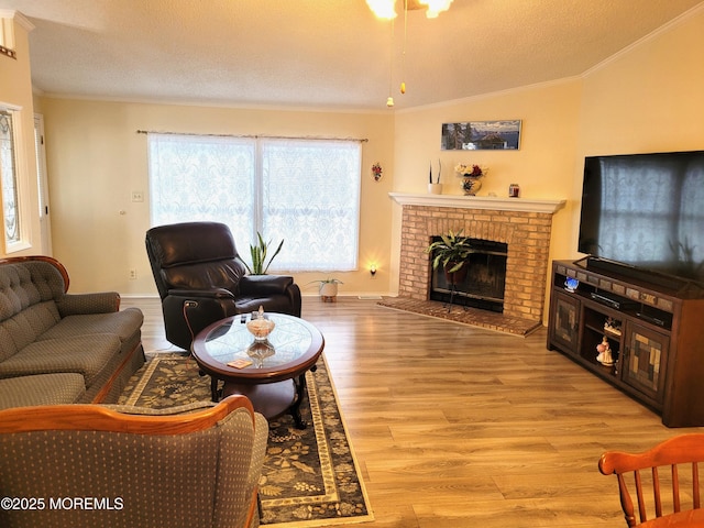 living room with a fireplace, lofted ceiling, light wood-type flooring, ornamental molding, and a textured ceiling