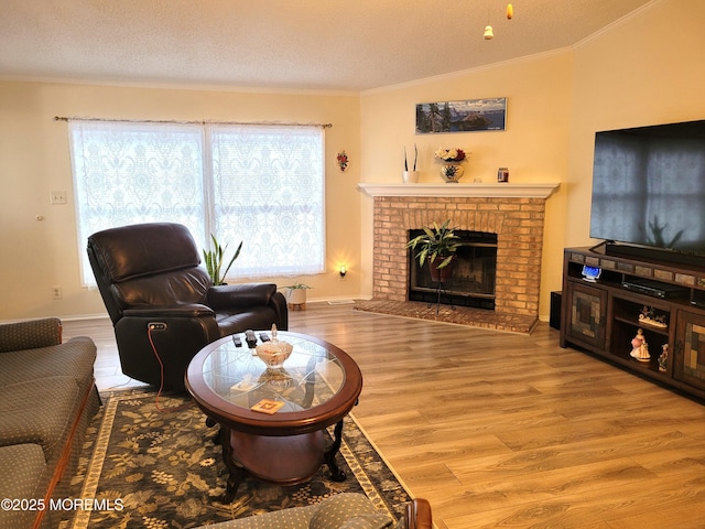 living room featuring a brick fireplace, ornamental molding, light hardwood / wood-style floors, and a textured ceiling