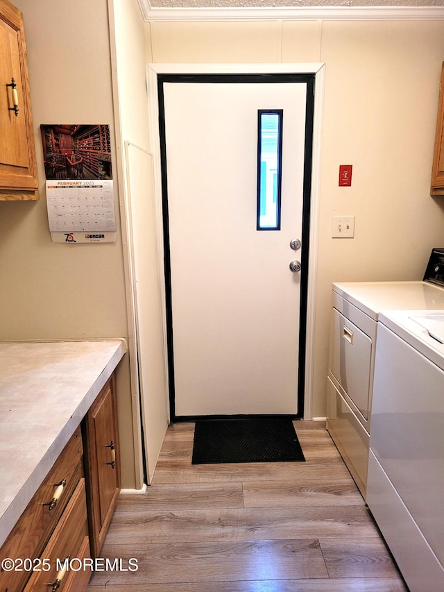 laundry area featuring independent washer and dryer, cabinets, and light wood-type flooring