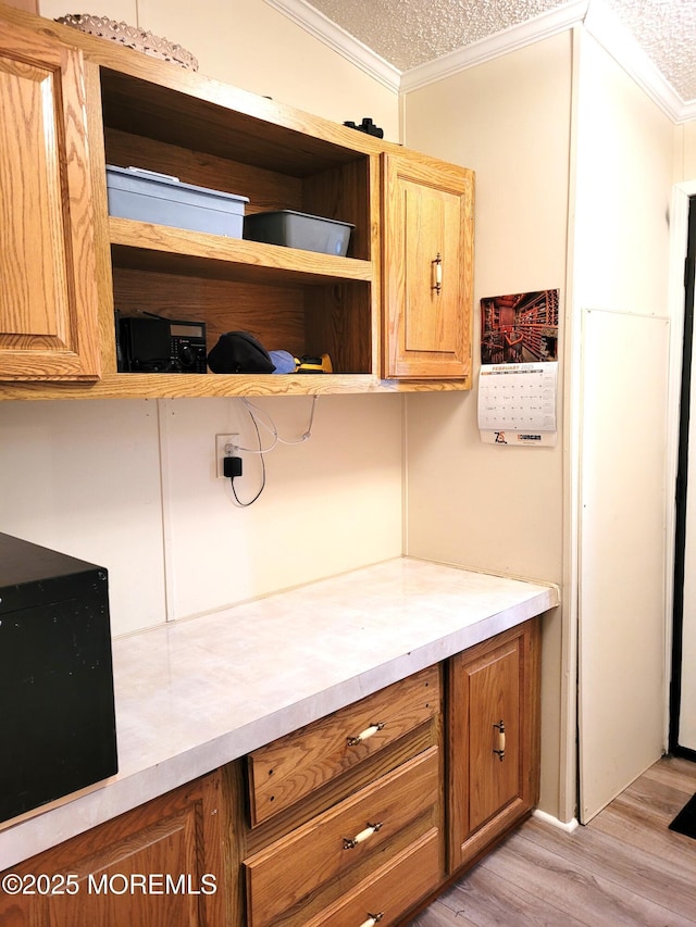 kitchen with ornamental molding, light hardwood / wood-style floors, and a textured ceiling