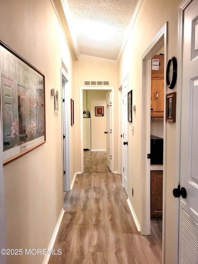 hall featuring ornamental molding, a textured ceiling, and light hardwood / wood-style flooring