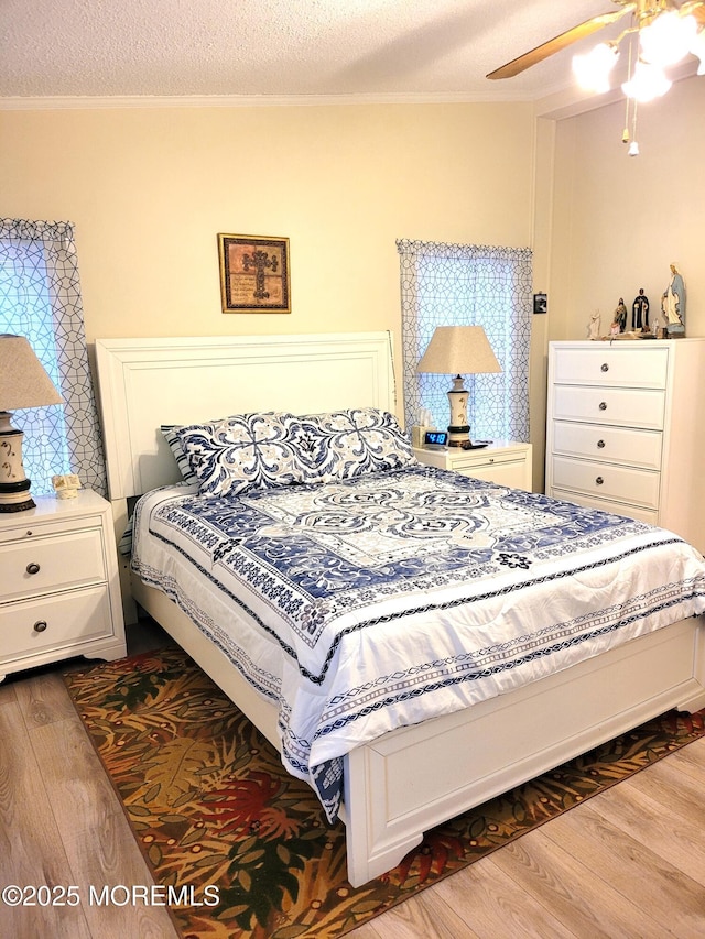 bedroom featuring ceiling fan, ornamental molding, dark hardwood / wood-style floors, and a textured ceiling