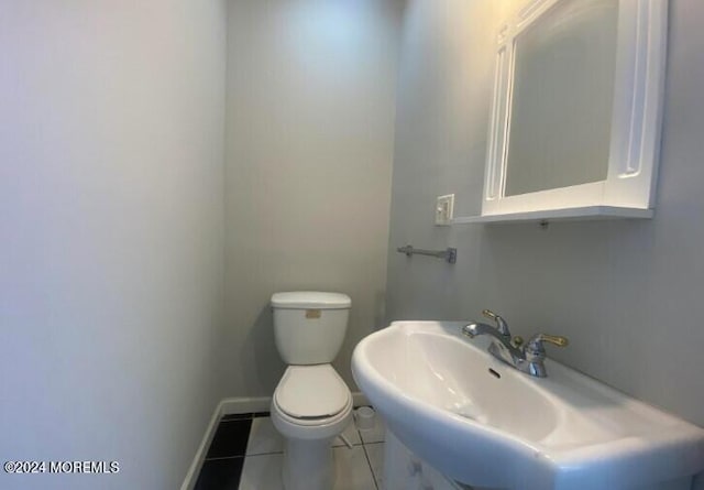 bathroom with toilet, tile patterned flooring, and sink