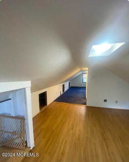 bonus room with hardwood / wood-style floors and vaulted ceiling