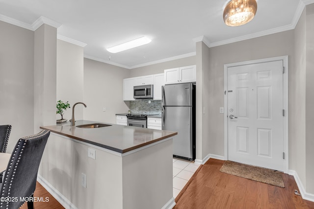 kitchen featuring sink, white cabinets, kitchen peninsula, stainless steel appliances, and light wood-type flooring