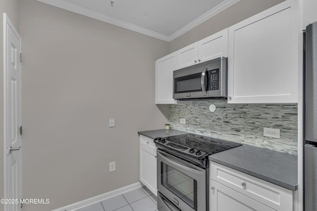 kitchen with light tile patterned floors, ornamental molding, stainless steel appliances, decorative backsplash, and white cabinets