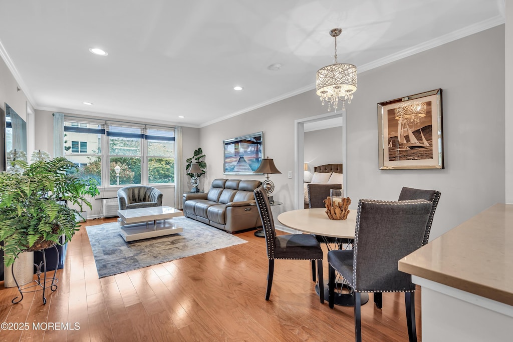 dining space with a notable chandelier, ornamental molding, and light hardwood / wood-style floors